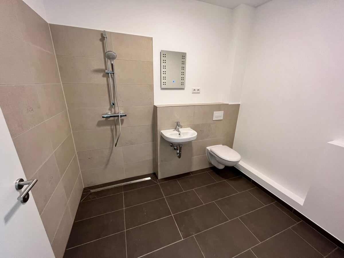 Barrierefreies Badezimmer mit bodengleicher Dusche, Haltegriff und Duschsitz