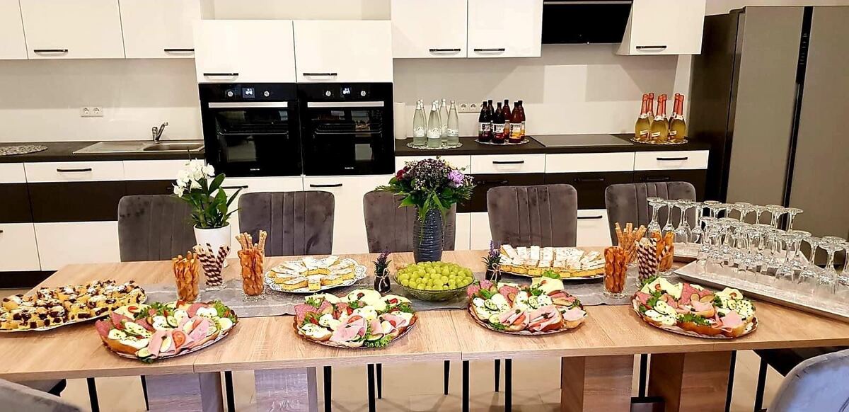 Vollausgestattete Gemeinschaftsküche mit langer Arbeitsplatte und Buffet