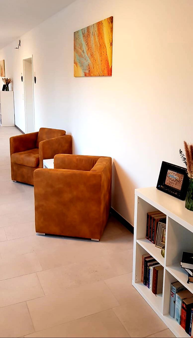 Sitzecke mit zwei cognacfarbenen Sesseln, Beistelltisch und Bild an der Wand